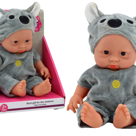 Egy kis totyogó baba szürke ruhában és koala sapkában